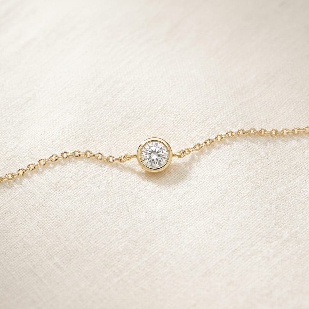 Duna bracelet: a fine gold chain with one bezel-set diamond, laid in a loose line on ivory linen