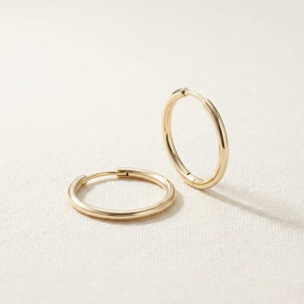Lluna hoops in yellow gold, one standing and one lying flat, on ivory linen