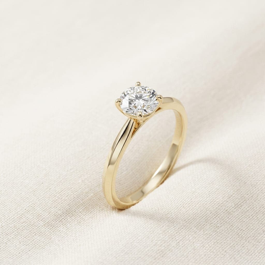 Orla Solitaire ring in yellow gold with a brilliant-cut diamond, seen from above on ivory linen