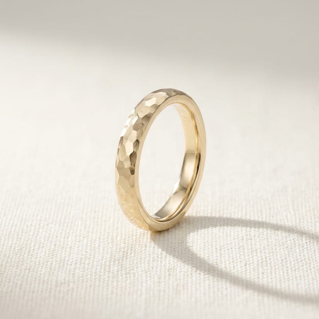 Petritxol hammered band in yellow gold, standing on edge in raking light