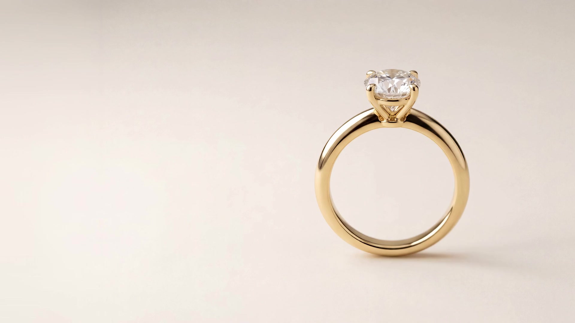The Orla Solitaire, a diamond ring in 18k recycled yellow gold, turning slowly against an ivory backdrop